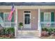 Inviting front porch with American flag, mint shutters, and a charming entrance door featuring transom window at 772 Preservation Pl, Mount Pleasant, SC 29464