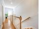 Bright hallway with hardwood floors, wood railing, and a large window at 772 Preservation Pl, Mount Pleasant, SC 29464