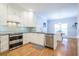 Open concept kitchen with stainless steel appliances, white cabinets, granite countertops, and hardwood floors at 772 Preservation Pl, Mount Pleasant, SC 29464