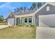 Inviting home exterior featuring a well-manicured lawn, two-car garage, and charming covered porch at 930 Dusk Dr, Summerville, SC 29486