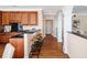Bright kitchen features dark countertops, wood cabinets, bar seating, and hardwood floors flowing through to the hallway at 1124 Clearspring Dr, Charleston, SC 29412