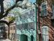 Charming teal townhome with black shutters and a covered entrance, nestled among historic brick buildings at 12 Elliott St # A, Charleston, SC 29401