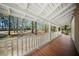 Long covered porch with stained wood flooring and white railings, offering a relaxing outdoor space at 1212 Pinopolis Rd, Moncks Corner, SC 29461