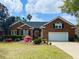 Charming brick home featuring a lush front yard, mature trees, and an attached two-car garage at 1213 Waterfront Dr, Mount Pleasant, SC 29464