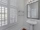 Bathroom with pedestal sink, decorative mirror, and natural light from shuttered window at 1369 Tidal Creek Cv, Charleston, SC 29412