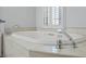 This bathroom features a luxurious soaking tub with tile surround and natural light from window at 1369 Tidal Creek Cv, Charleston, SC 29412