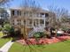 Elegant two-story brick home with a double front porch, white columns, and professionally landscaped front yard at 1369 Tidal Creek Cv, Charleston, SC 29412