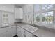 Well-lit kitchen sink area with white cabinets, granite countertops, and plantation shutters at 1369 Tidal Creek Cv, Charleston, SC 29412