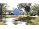 A charming blue home sits alongside a pond, featuring a quaint balcony, a well-kept lawn and attached garage at 1984 Shadetree Blvd, Johns Island, SC 29455