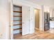Open pantry showing wooden shelves, leading to a stainless steel refrigerator in the kitchen at 2072 Middleburg Ln, Mount Pleasant, SC 29464