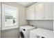 Neat laundry room with bright cabinets and a window with view to the neighborhood at 3020 Plumier Pl, Charleston, SC 29414