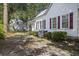 Back exterior view of the white home with red shutters, landscaping, and detached building at 311 Black St, Walterboro, SC 29488