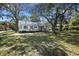 Wide shot of charming white home with a metal roof, red shutters, and mature trees at 311 Black St, Walterboro, SC 29488