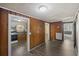 Living room featuring wood paneled walls, gray wood-look flooring, and open access to kitchen and bathroom at 311 Black St, Walterboro, SC 29488