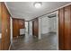 Open living room with wood paneled walls and gray wood-look flooring, showcases doorway to connected living space at 311 Black St, Walterboro, SC 29488