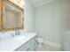 Bathroom featuring a blue vanity with a white marble top, gold mirror and white subway tile at 3419 Myrtle St, Edisto Island, SC 29438