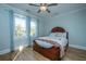 Bright bedroom with light blue walls, hardwood floors, ceiling fan and large windows with picturesque outdoor views at 3419 Myrtle St, Edisto Island, SC 29438