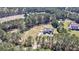 Aerial view of a home nestled among trees with a well-manicured lawn and pond in the distance at 4846 Causey Pond Rd, Awendaw, SC 29429