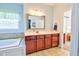 Bright primary bathroom featuring cherry vanity and soaking tub next to walk-in closet at 4846 Causey Pond Rd, Awendaw, SC 29429