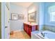 Bright primary bathroom featuring a cherry vanity with framed art and a soaking tub at 4846 Causey Pond Rd, Awendaw, SC 29429