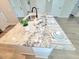 Kitchen island features a sleek sink and elegant place settings on a granite countertop at 609 Sienna Way, Summerville, SC 29486