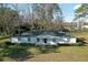 Well-maintained single-story home with white facade, complemented by green shrubbery and mature trees at 6156 Badham Dr, Reevesville, SC 29471