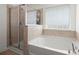Well-lit bathroom showcasing separate tub and shower with neutral tiling and window with privacy blinds at 686 Redbud Ln, Summerville, SC 29486