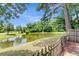 Scenic pond view framed by mature trees and a charming fence, offering a serene outdoor escape at 9360 S Moreto Cir, Summerville, SC 29485