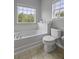 Bathroom featuring a soaking tub, toilet, and a large window that provides natural light at 9400 Divot Ln, Summerville, SC 29485