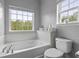 A clean, bright bathroom featuring a soaking tub, toilet, and large window for natural light at 9400 Divot Ln, Summerville, SC 29485