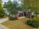 Aerial view of a red brick home with a two car garage and a driveway in a lush green neighborhood at 102 Kapalua Run, Summerville, SC 29483