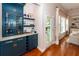 Bar area with custom blue cabinets, glass shelving, hardwood floors and adjacent to the living room at 1021 Barfield St, Charleston, SC 29492