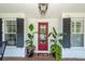 Inviting covered porch features a vibrant red door, complemented by stylish potted plants at 1021 Barfield St, Charleston, SC 29492