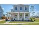 Charming two-story home with a covered front porch, adorned with hanging ferns and classic rocking chairs at 106 Wood Sage Run, Summerville, SC 29485