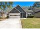 Charming home featuring a two-car garage, manicured lawn, and classic architectural details under a clear blue sky at 125 Mansfield Blvd, North Charleston, SC 29418