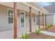 Inviting front porch with stained wood columns, a sage green front door, and manicured landscaping at 136 Mitch Ln, Holly Hill, SC 29059