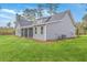 View of the rear of the home with a screened in porch, gray siding, green lawn and trees in the background at 136 Mitch Ln, Holly Hill, SC 29059