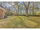 Spacious backyard with mature trees and a wooden fence, perfect for outdoor activities at 140 Wampee Curve, Summerville, SC 29485