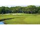 Scenic golf course view featuring sand traps, marsh, and lush green fairways surrounded by mature trees at 157 High Hammock Villas, Seabrook Island, SC 29455