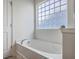 Modern bathroom featuring a tub, glass block window, and stylish fixtures and bright neutral colors at 189 Weeping Cypress Dr, Moncks Corner, SC 29461