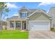 Inviting two-story home featuring a front porch, an attached garage, and a vibrant green lawn at 189 Weeping Cypress Dr, Moncks Corner, SC 29461