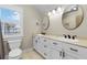 Bathroom with double sinks, white cabinets, and a bright window offering pleasant natural light at 212 Ocean Blvd, Isle of Palms, SC 29451