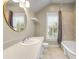 Well-lit bathroom with a round mirror, white vanity, tan tile, and a window with plantation shutters at 212 Ocean Blvd, Isle of Palms, SC 29451
