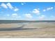 Expansive beach view with soft sand and ocean waves under a bright blue sky with fluffy white clouds at 212 Ocean Blvd, Isle of Palms, SC 29451