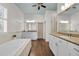 Elegant bathroom with dual vanities, soaking tub, walk-in shower, white cabinets, and hardwood floors at 212 Ocean Blvd, Isle of Palms, SC 29451