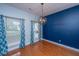 Dining room with wood floors, dark blue accent wall, chandelier and windows with blue patterned curtains at 218 Candleberry Cir, Goose Creek, SC 29445