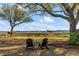 Inviting backyard scene with two Adirondack chairs offering a serene waterfront view under a shady tree at 2410 Kemway Rd, Johns Island, SC 29455