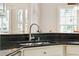 Close-up of a stainless steel kitchen sink, black countertops, and white cabinets, showcasing modern design at 2737 Old Forest Dr, Seabrook Island, SC 29455