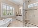 Bright bathroom featuring a glass shower, soaking tub, marble countertop, and elegant fixtures at 278 Furman Farm Pl, Daniel Island, SC 29492
