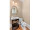Neutral powder room with a vanity and sink with an arched mirror and hardwood floors at 278 Furman Farm Pl, Daniel Island, SC 29492